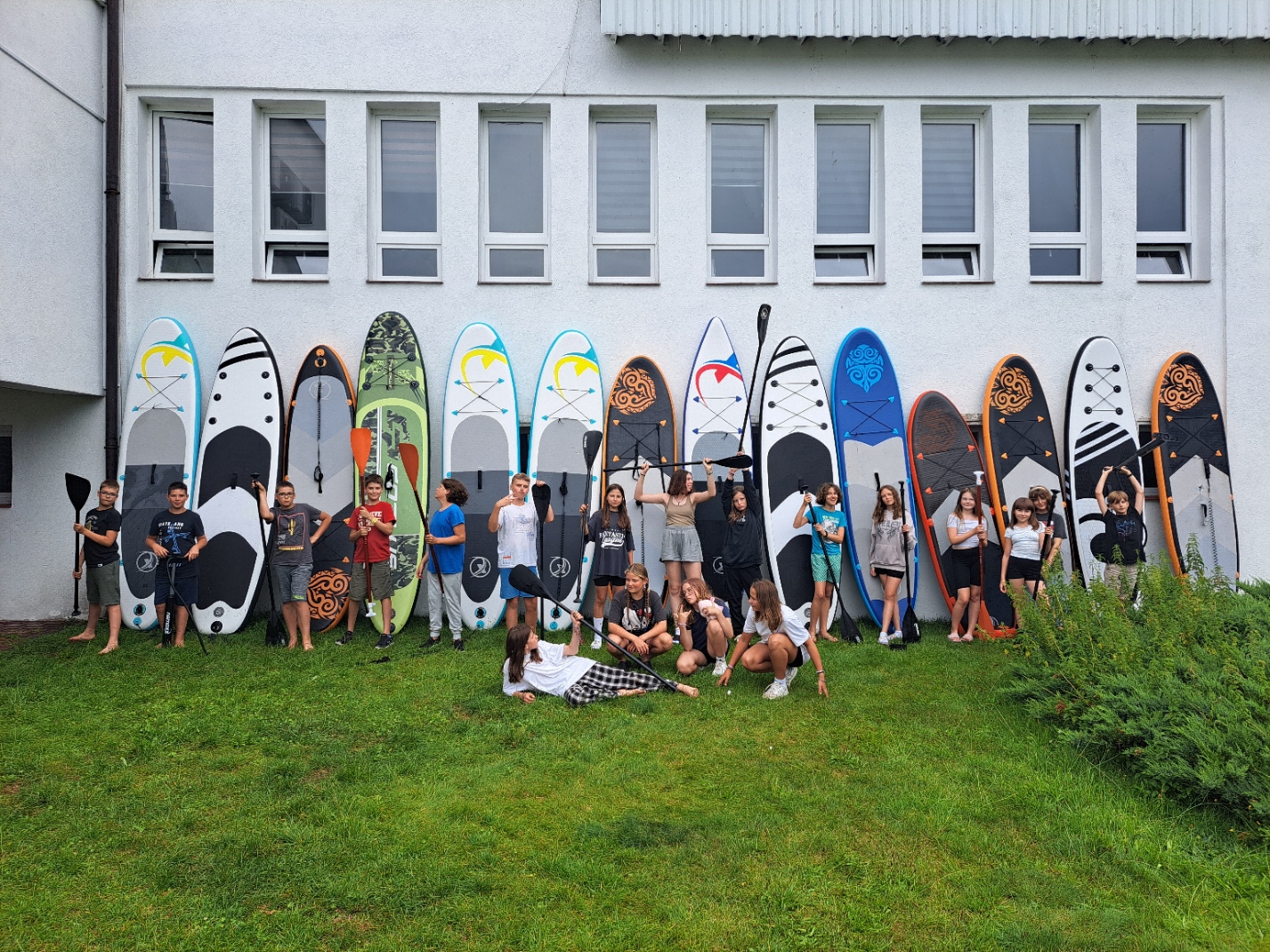 Grupa dzieci z deskami SUP przed ośrodkiem